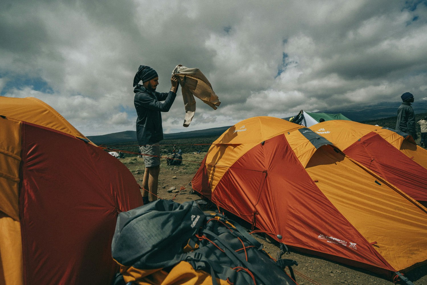 Man shaking pants outside tent on Mount Kilimanjaro