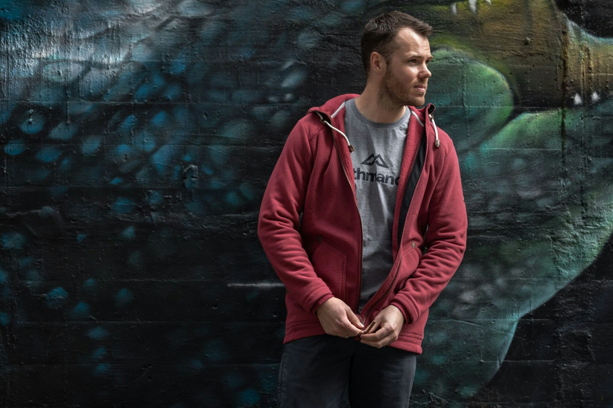 The Flaxmere Longline Jacket is a stylish fleece layer. Image of a man wearing the red Flaxmere Longline Jacket in an urban environment.