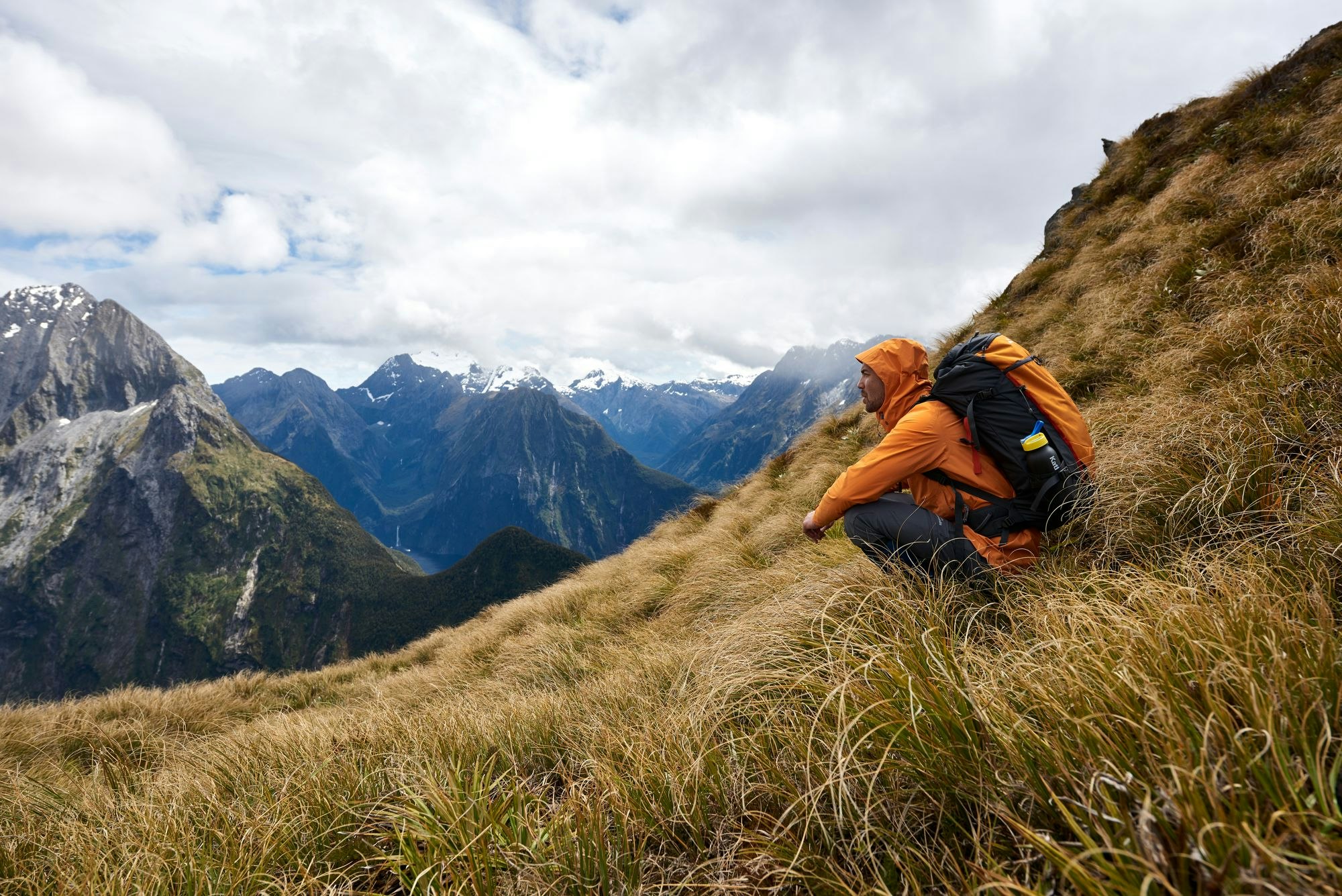 Man squatting and looking at view at Milford Sound
