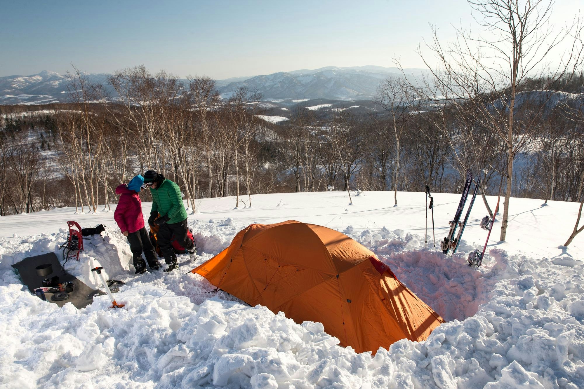 Snow poses its own challenges for keeping your tent clean Two campers in the snow with an orange tent