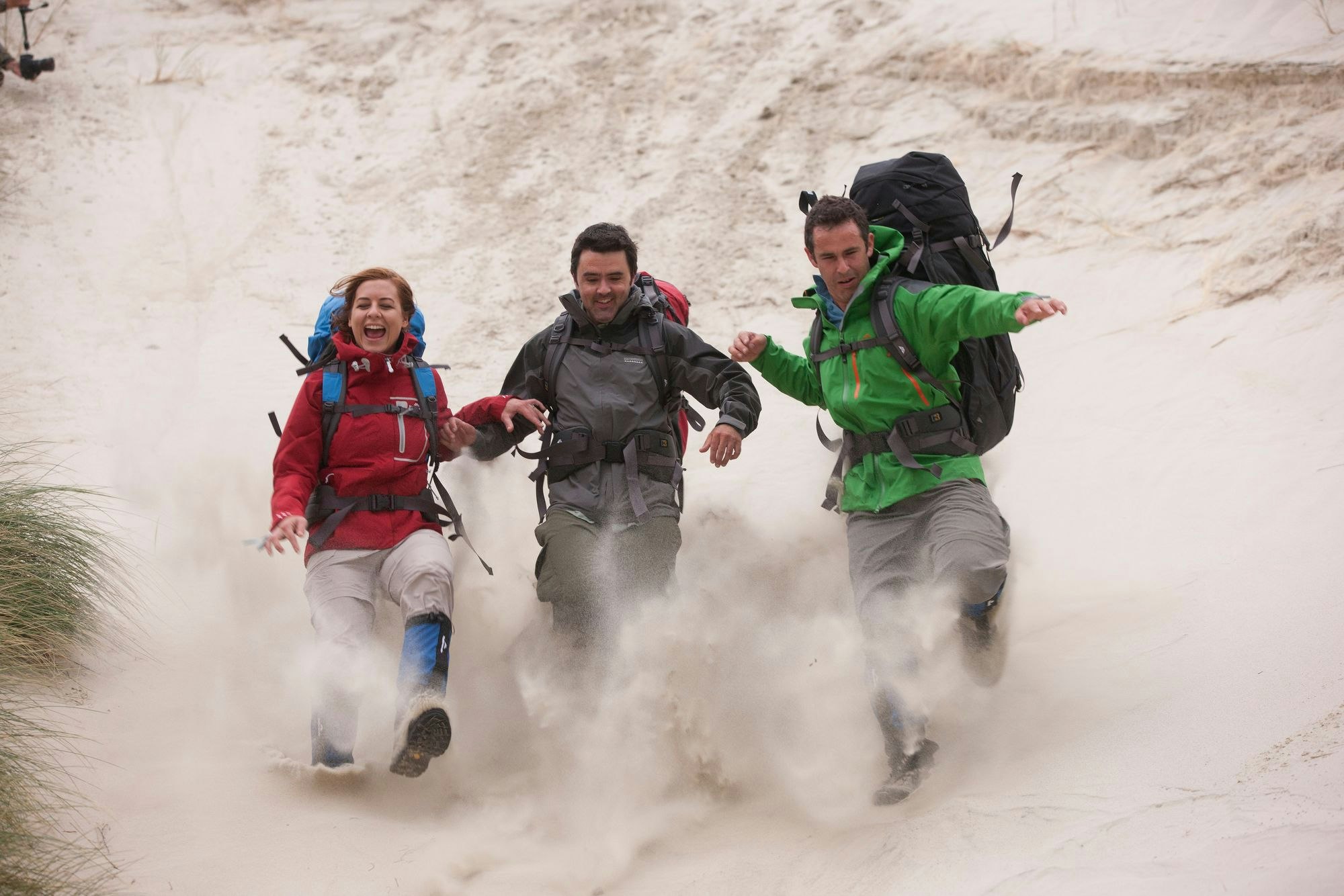 Three hikers running down sand dune on Great Walk of New Zealand